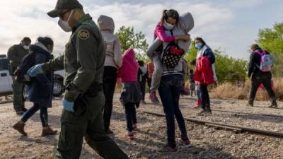 Una madre e hija migrantes, de 8 años, de Honduras llegan con otros solicitantes de asilo a Texas después de cruzar el Río Bravo desde México el 26 de marzo de 2021 en Peñitas, Texas. AFP