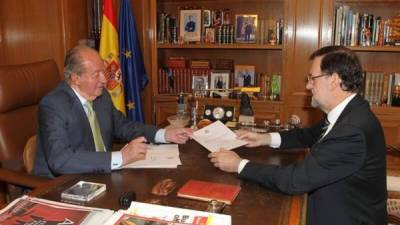 El rey Juan Carlos entrega la carta de renuncia al primer ministro de España Mariano Rajoy en la Palacio de la Zarzuela en Madrid. AFP
