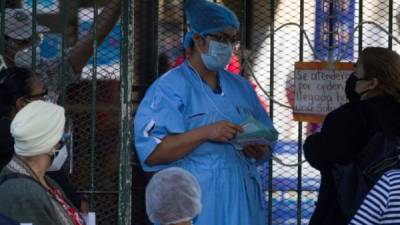 Una trabajadora de la salud habla con personas que buscan atención medica en el Instituto Nacional Cardiopulmonar (Hospital del Tórax) en Tegucigalpa. EFE