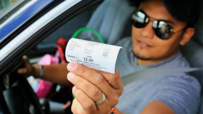 El conductor Carlos Mejía muestra el nuevo recibo por doce lempiras por carro de dos ejes. Fotos: Jordan Perdomo