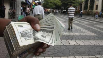 Un cambista muestra un fajo de billetes cerca del parque central de San Pedro Sula. El valor del dólar se ha incrementado casi tres lempiras desde 2011.