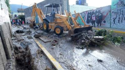 Operarios de maquinaria pesada remueven escombros. EFE.