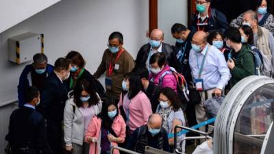 Pedestrians wearing face masks cross a road during a Lunar New Year of the Rat public holiday in Hong Kong on January 27, 2020, as a preventative measure following a coronavirus outbreak which began in the Chinese city of Wuhan. (Photo by Anthony WALLACE / AFP)