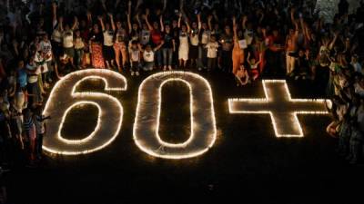 People light candles and form the 60+ sign during the Earth Hour environment campaign in Cali, Valle del Cauca department, Colombia, on March 24, 2018. - Earth Hour, which started in Australia in 2007, is being observed by millions of supporters in 187 countries, who are turning off their lights at 8.30pm local time in what organisers describe as the world's 'largest grassroots movement for climate change'. (Photo by Luis ROBAYO / AFP)
