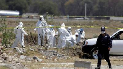 Peritos forenses realizan el levantamiento de cuerpos hallados entre desechos.