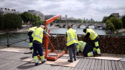 Trabajadores del Ayuntamiento de París eliminan paneles repletos de 'candados del amor' colocados en las barandas del Puente de las Artes . AFP