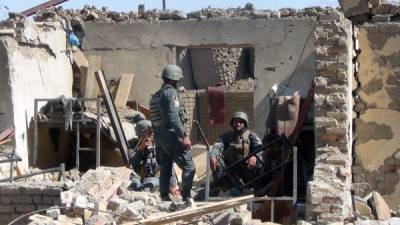 Policías afganos entre los escombtos del ataque de este domingo.