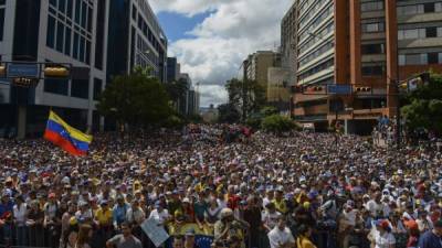 La gente mientras escuchaba al presidente de la Asamblea Nacional de Venezuela, Juan Guaidó (fuera de trama), durante un mitin de oposición en masa contra Nicolás Maduro, en el que se declaró a sí mismo el 'presidente interino' del país, en el aniversario de un levantamiento de 1958 que derrocó a una dictadura militar en Caracas.