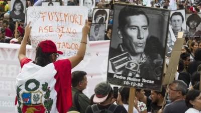 Manifestantes participan con banderas y pancartas durante una marcha contra el indulto otorgado al expresidente Alberto Fujimori. EFE