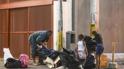 Un hombre y sus dos hijas buscan sobras de comida en la basura para poder alimentarse. AFP.