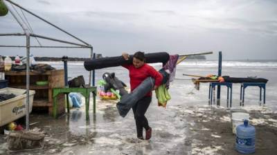 Una mujer quita sombrillas de la playa cuando las fuertes olas llegan a la costa debido al huracán Grace, que alcanzó la categoría 2, en Boca del Río, Veracruz. Foto AFP