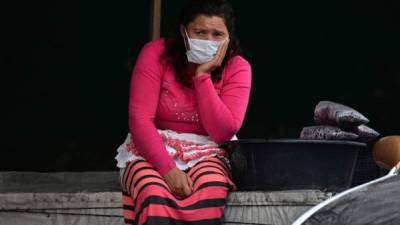 Una mujer que vende fruta usa una máscara facial como medida preventiva contra la propagación del nuevo coronavirus. Foto AFP