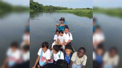 El profesor Hugo Pinto traslada a sus alumnos en un cayuco por el río San Juan en Boca Cerrada.