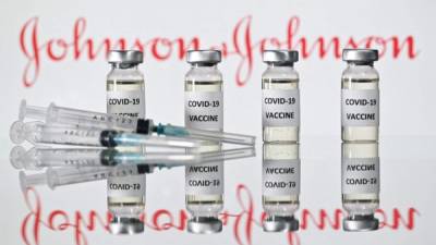 Una foto de archivo tomada el 17 de noviembre de 2020 muestra viales con adhesivos de vacuna Covid-19 adheridos y jeringas con el logotipo de la compañía farmacéutica estadounidense Johnson & Johnson en Londres.