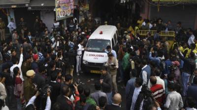 Una ambulancia rodeada de medios de comunicación sale de una calle que conduce a una fábrica después de un incendio en el área de Anaj Mandi de Nueva Delhi . Foto AFP