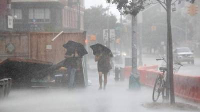 Dos personas caminan bajo el fuerte viento y la lluvia durante la tormenta tropical Isaías en Nueva York, el 4 de agosto de 2020.