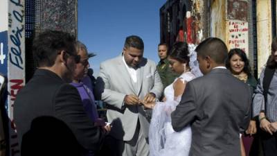 Brian Houston le pone un anillo a su prometida Evelia Reyes durante la celebración de su boda en una de las puertas de la valla fronteriza. EFE