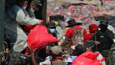 Soldados y militares distribuyendo alimentos en el vertedero municipal de Tegucigalpa. Foto AFP