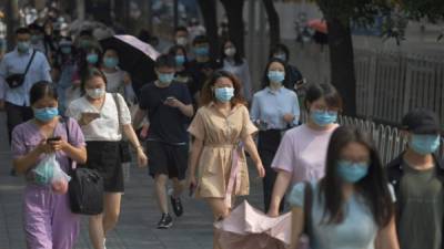 Las personas usan máscaras mientras caminan hacia el trabajo en Beijing. Foto AFP