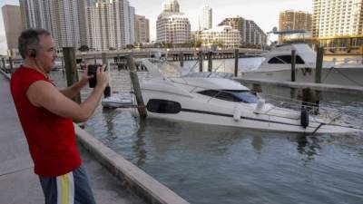 Un hombre hace fotos a un barco hundido en Miami Beach, Florida. EFE/Archivo