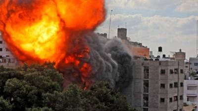 Una imagen muestra una bola de fuego que envuelve el edificio de Al-Walid que fue destruido en un ataque aéreo israelí en la ciudad de Gaza. Foto AFP