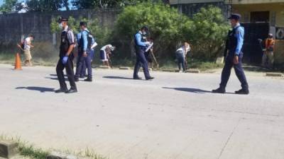 Los oficiales de la Policía Nacional observan a los ciudadanos realizando trabajo comunitario.