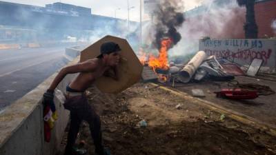 Un manifestante se protege durante una confrontación con miembros de la Guardia Bolivariana este 3 de mayo de 2017, en Caracas (Venezuela). EFE