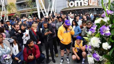 People gather around a makeshift memorial for former NBA and Los Angeles Lakers player Kobe Bryant after learning of his death at LA Live plaza in front of Staples Center in Los Angeles on January 26, 2020. - NBA legend Kobe Bryant died January 26, 2020 in a helicopter crash in suburban Los Angeles, celebrity website TMZ reported, saying five people are confirmed dead in the incident. (Photo by Frederic J. Brown / AFP)