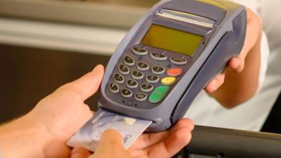Un cliente pasa su tarjeta de crédito por una máquina POS en una tienda.