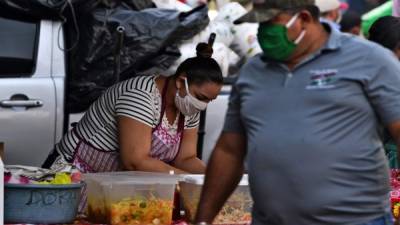 La gente usa máscaras faciales contra la propagación del nuevo coronavirus en un mercado en Tegucigalpa. Foto AFP