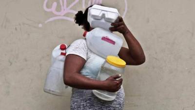 Una mujer carga botes de agua para su consumo este martes, en Tegucigalpa (Honduras). Más de 900.000 personas están en situación de inseguridad alimentaria por la sequía que afecta a gran parte de Honduras, especialmente el llamado Corredor Seco, una cifra que puede aumentar hasta más de un millón durante los próximos meses.