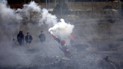 Un joven palestino sostiene una granada de gas lacrimógeno lanzada por miembros del Ejército israelí. EFE