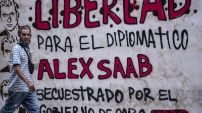 Un hombre pasa junto a un grafiti que dice 'Libertad para el diplomático Alex Saab, secuestrado por el gobierno de Cabo Verde' en Caracas. Foto AFP