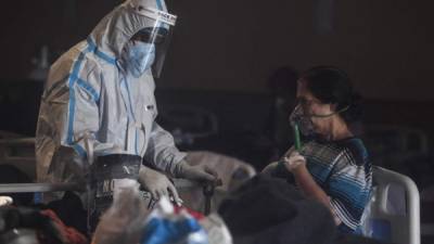Un trabajador de la salud que usa equipo de protección personal atiende a un paciente con coronavirus dentro de un salón de banquetes. Foto AFP
