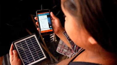 Katherine Juliet López, una estudiante de la escuela trébol de Ciudad España usa un dispositivo móvil con un panel solar en Támara, al norte de la capital. Foto EFE