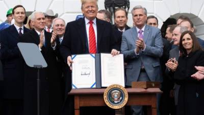 US President Donald Trump holds up the signed United States - Mexico -Canada Trade Agreement, known as USMCA, during a ceremony on the South Lawn of the White House in Washington, DC, January 29, 2020. - The USMCA, the fruit of years of negotiation between the three key trading partners, is billed as an update to the 1994 North American Free Trade Agreement, which Trump had long lambasted as a job killer and threatened to scrap outright. (Photo by SAUL LOEB / AFP)