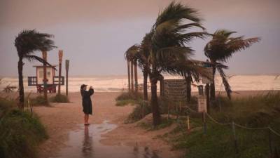 Una mujer toma una fotografía cuando los efectos del huracán Dorian comienzan a sentirse en Cocoa Beach, Florida. Foto AFP