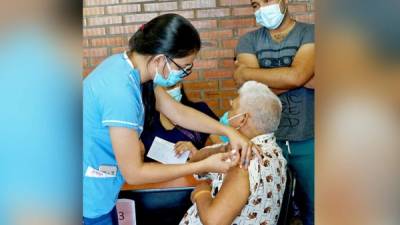 Enfermera vacuna a un hombre de la tercera edad.