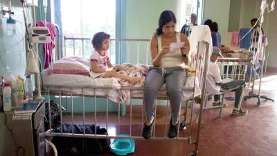 Ashley, una niña de 3 años, en el hospital Universitario de Caracas, mientras su madre, Oriana Pacheco, lee una receta.