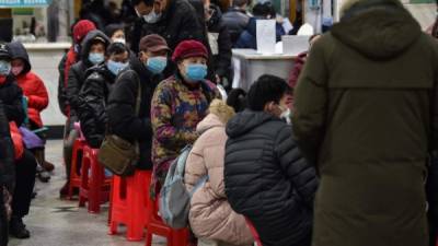 Las personas que usan máscaras faciales para ayudar a detener la propagación de un virus mortal que comenzó en la ciudad, esperan en el Hospital de la Cruz Roja de Wuhan. Foto AFP