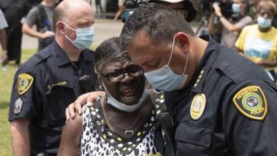 El jefe de la policía de Houston, Art Acevedo, reza con una mujer mientras las personas esperan en la fila para asistir a la presentación pública de George Floyd en la iglesia Fountain of Praise. Foto AFP