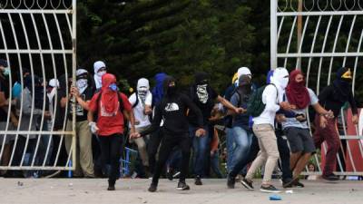 Estudiantes de la Universidad Nacional Autónoma de Honduras (UNAH) se enfrentan con la policía antidisturbios durante una protesta contra la reelección del presidente Juan Orlando Hernández.