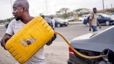 Un vendedor ambulante de combustible abastece a un cliente en Lagos. El mercado negro florece en medio de la escasez de diversos productos.
