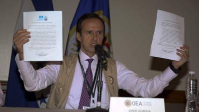 El jefe de la misión de observadores de la OEA mostraba los acuerdos firmados por los dos candidatos.