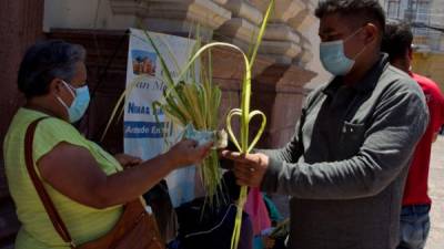 Una mujer compra ramos de palma a la entrada de la Catedral San Miguel Arcángel de Tegucigalpa. EFE