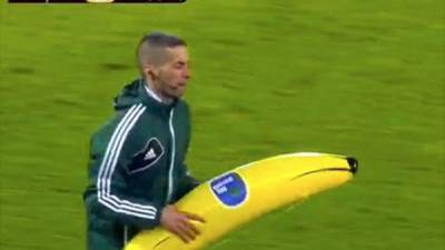 Un árbitro retira del campo la banana gigante que le lanzaron a Gervinho.
