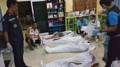 Agentes de la policía forense y miembros de los servicios de emergencias tailandeses permanecen junto a los cuerpos de varios de los miembros de una misma familia asesinados durante el asalto de un grupo armado a la casa de un jefe local en la provincia tailandesa de Krabi, en Tailandia, hoy, 11 de julio. EFE