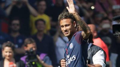 Paris Saint-Germain's Brazilian forward Neymar waves to the crowd as he arrives on the football field during his presentation to the fans at the Parc des Princes stadium in Paris, on August 5, 2017.Brazil superstar Neymar will watch from the stands as Paris Saint-Germain open their season on August 5, 2017, but the French club have already clawed back around a million euros on their world record investment. Neymar, who signed from Barcelona for a mind-boggling 222 million euros ($264 million), is presented to the PSG support prior to his new team's first game of the Ligue 1 campaign against promoted Amiens. / AFP PHOTO / Thomas Samson