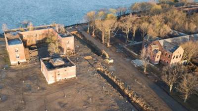 Fotografía aérea donde muestra una retroexcavadora junto a grandes trincheras funerarias y edificios abandonados en Hart Island, ubicada en el sonido de Long Island, frente a la costa del Bronx. EFE