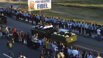 Los cubanos asisten al paso de la urna con las cenizas del líder cubano Fidel Castro desde la Plaza de la Revolución en Santiago de Cuba el 4 de diciembre de 2016 en su camino hacia el cementerio / AFP PHOTO / RODRIGO ARANGUA